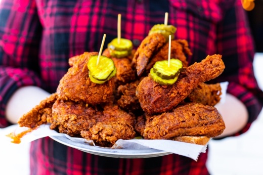 Man holding a plate of hot chicken