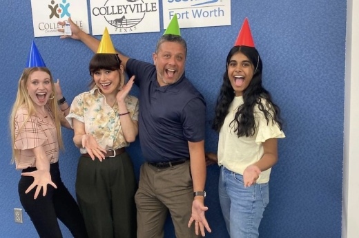 four people in party hats smile and pose