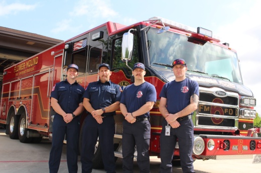Firefighters stand in front of a fire truck