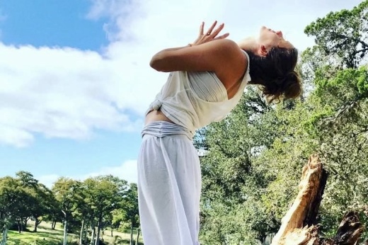 a woman performs a yoga pose by bending backward