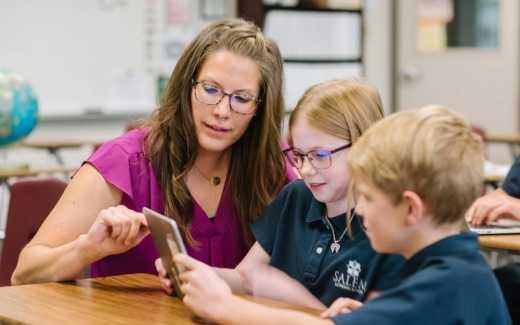 teacher works with two students at a desk
