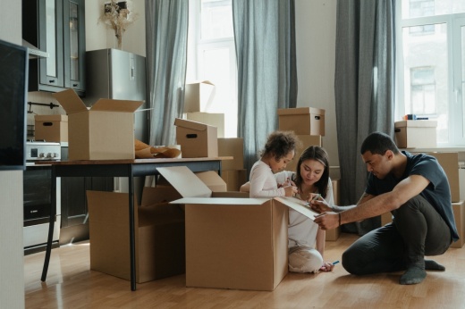 a family sits inside their home surrounded by moving boxes