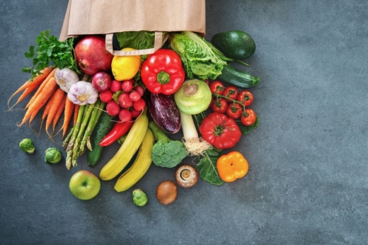 Fruits and vegetables spilling out of a brown paper bag