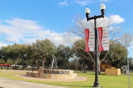 Depot Plaza sign in the background with light pole with Tomball Together flags in foreground