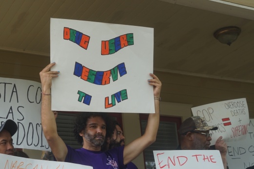 Man holding a sign that says "drug users deserve to live"