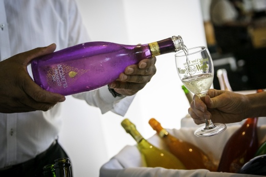 Wine is poured from a purple bottle into a glass.