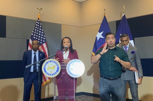a woman speaks at a podium while someone standing beside her signs what she is saying