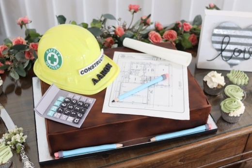 a custom cake with a hard hat, calculator and construction document entirely made of cake