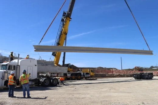 a large beam is being lowered horizontally as part of a construction project