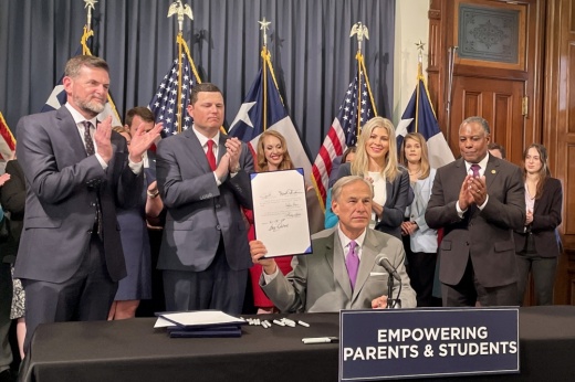 Flanked by Texas lawmakers and supporters, Gov. Greg Abbott (center) signs House Bill 900, which will create new standards for school library books.