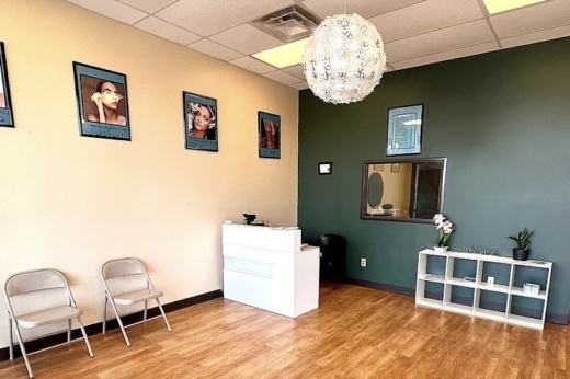 Interior of a spa with a counter, TV, chairs for waiting and a shelf.