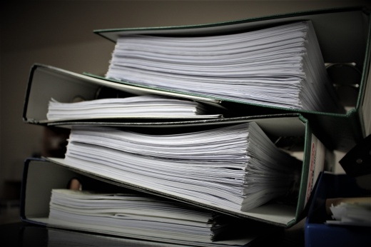 The photo shows binders stacked with papers inside.