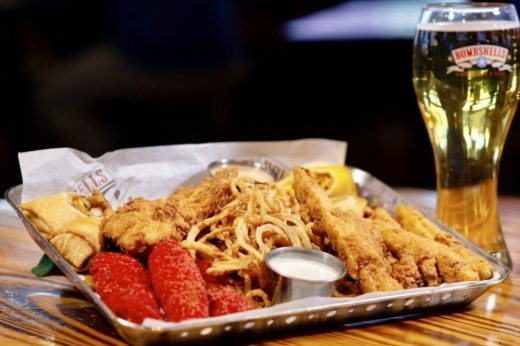 Trey of wings, fries, and onion rings next to a pint of beer