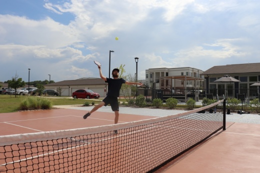 A pickleball player hits a ball out of the air.