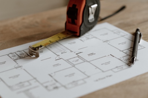 Pen and blueprint paper with measuring tape on desk