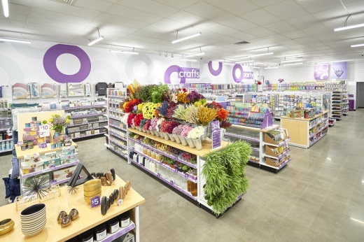 A discount store with shelves of items, including fake flowers. Purple rings are painted on the walls.