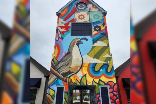 A brightly painted shopping center facade with a bird and flowers