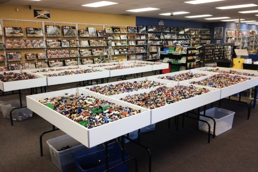 A large assortment of scrambled lego pieces on tables in a resale store