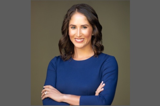 A headshot of Angela Colmenero smiling with her arms crossed.