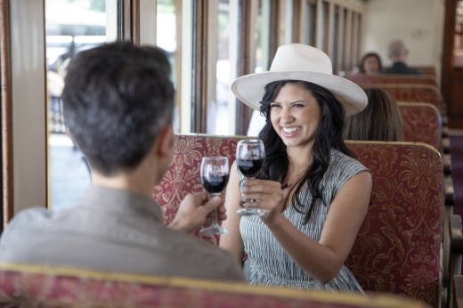 two people on a train cheering with glasses of wine