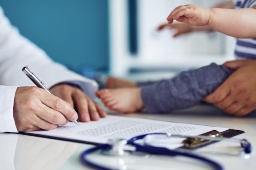 A stock photo of a doctor filling out paperwork for a pediatric patient