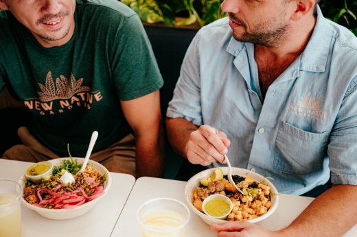 Two men sit at a table eating grain bowls from Honest Mary's.