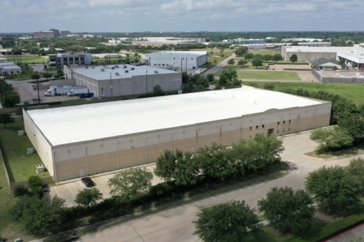 A large square building surrounded by trees in a business park
