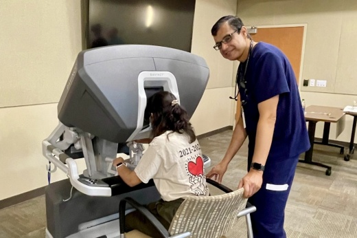 A doctor overviews a high-school student using an advanced medical procedure machine