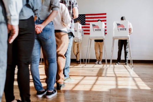 A line of people getting ready to vote as well as some voting booths