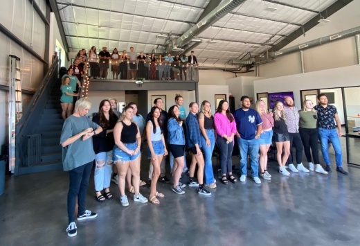 A group of people pose for a photo inside an office building.