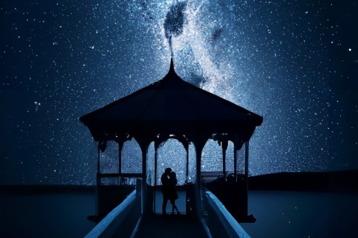 two people stand under a covered pavilion against a night sky