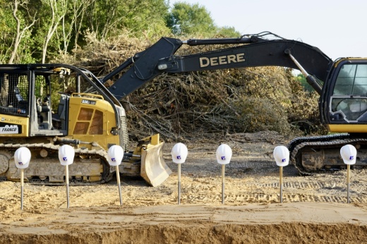 A line of hard-hats in front of bulldozer for groundbreaking ceremony of new school