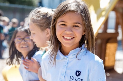 three children in valor uniforms with one child smiling at the camera