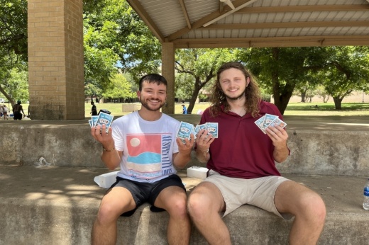the owners of the playing card company sitting and holding up the cards