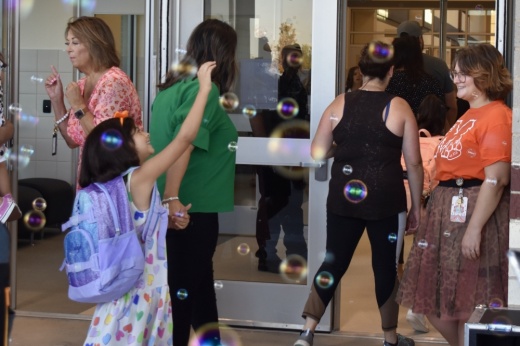 girl walks into school door while walking through floating bubbles