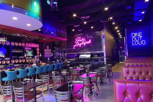 Interior view of trendy sushi restaurant and bar with neon lights, purple leather seats, and a rock and roll aesthetic theme