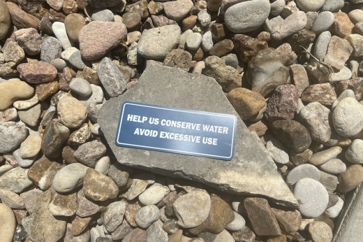 larger rock among smaller rocks that says help us conserve water avoid excessive use
