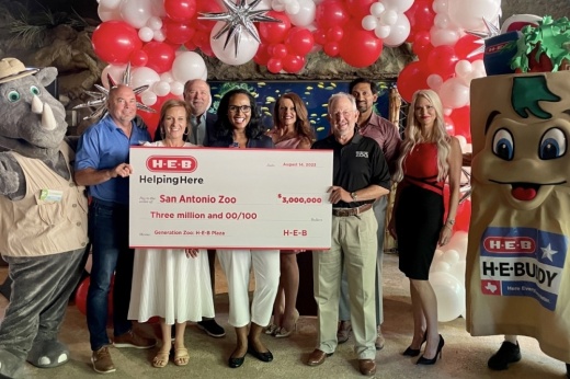 a group poses with a large check from H-E-B