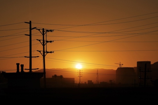 The sun rising behind power lines.