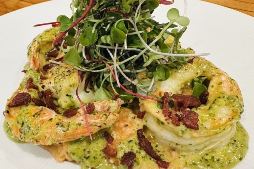 A popular brunch menu item at Hudson's on the Bend is shrimp and grits, made with smoked tomato grits, arugula pesto, white wine sauce, wood-fired shrimp and duck bacon. (Courtesy Hudson's on the Bend/Community Impact)