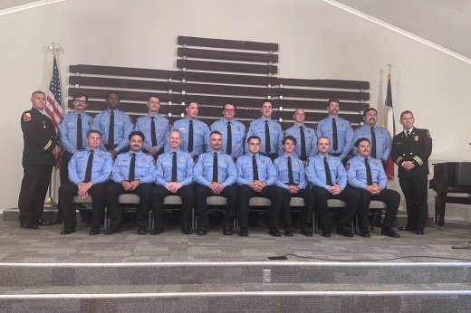 17 new firefighters sit on a stage for their graduation ceremony