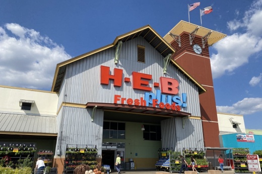 An H-E-B plus! store front with people walking inside.
