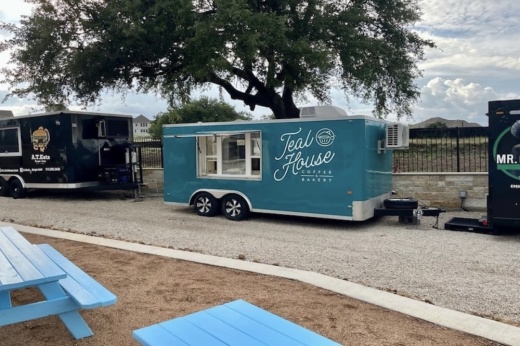 A blue food truck trailer labeled teal house coffee and bakery