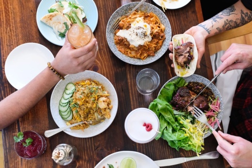 A table is filled with food and hands reach out to pick up the food