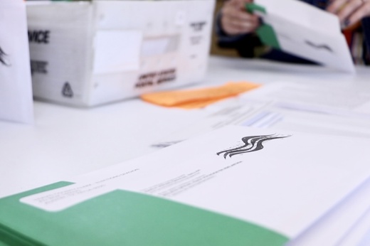 Green and white mail-in ballots on a table