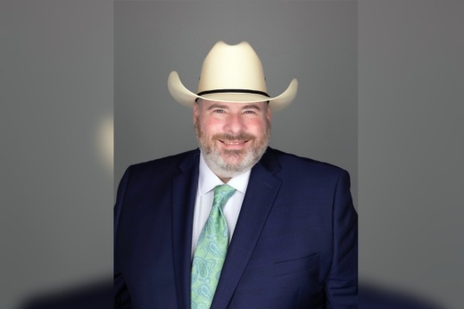 a man in a suit and a cowboy hat poses for a photo