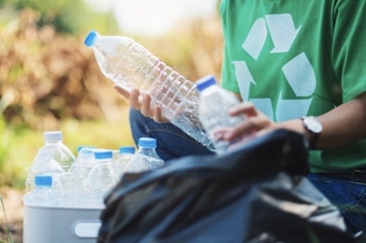 Picture of someone placing plastic bottles in a recycling container