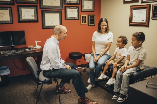 A doctor talks to a mother and two children at a doctor's office.