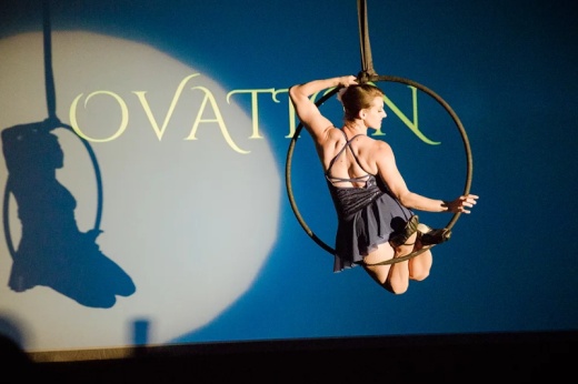 A woman does air acrobatics with a spotlight on her at a previous Ovation gala.