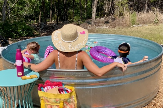 A woman and two children relax in a stock tank pool